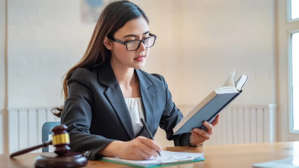 a personal injury lawyer sitting at a desk reading and writing on a book